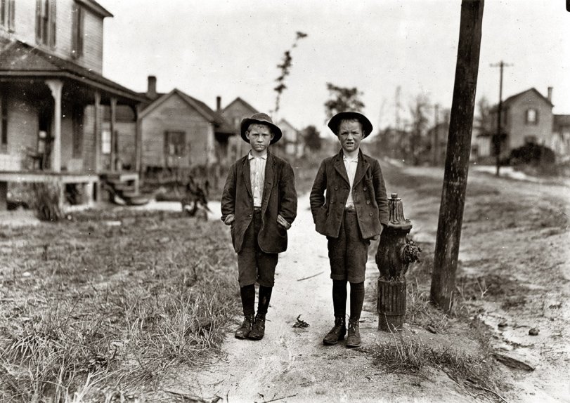 Goes to School Now (He Says) On streets near Daniel Mill. Lincolnton, North Carolina. November 1908. Right hand boy is Dan Biggerstaff. 10 years old. Has worked three years. Goes to school now (he says). Left hand, John Erwin. Said 11 years old. Has worked nights. Photograph by Lewis Wickes Hine. View full size.