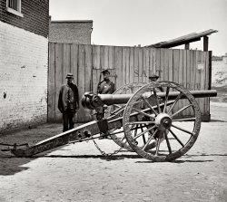 April 1865. Richmond, Virginia. "Federal soldier guarding Whitworth gun on wharf awaiting shipment." Wet plate glass negative. View full size.