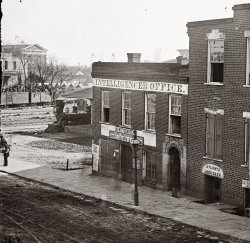 "The War in the West." 1864 photo (half of a stereograph) by George N. Barnard. Atlanta Intelligencer newspaper office by the railroad depot. Exposure times were so long that anyone walking appears only as an ectoplasmic blur. View full size. Note tents in background and troop train with soldiers atop the boxcars.