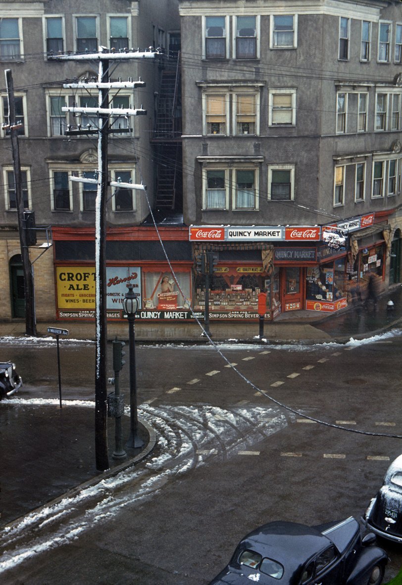 125 Pleasant Street: 1941 Street corner, Brockton, Massachusetts. January 1941. Two blurry figures pass by a fire hydrant in this time exposure by Jack Delano. View full size. Using the 125 above the door and the street sign as clues, we were able to find this building in Google Maps: 125 Pleasant Street at North Warren Avenue. It's the building to the right with the white roof, and seems to be more or less unchanged. Some of the apartments above the store are on the market as condos. The building the photographer used as his vantage point has disappeared, replaced by a parking lot.
