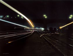 March 1943. "Activity in the Santa Fe R.R. yard, Los Angeles, Calif. All switch lights, headlights and lamps have been shaded from above in accordance with blackout regulations. The heavy light streaks are caused by paths of locomotive headlights and the thin lines by lamps of switchmen working in the yard. Santa Fe R.R. trip." View full size. 4x5 Kodachrome transparency by Jack Delano, who seems to have been among the earliest photographers of light trails in color.
