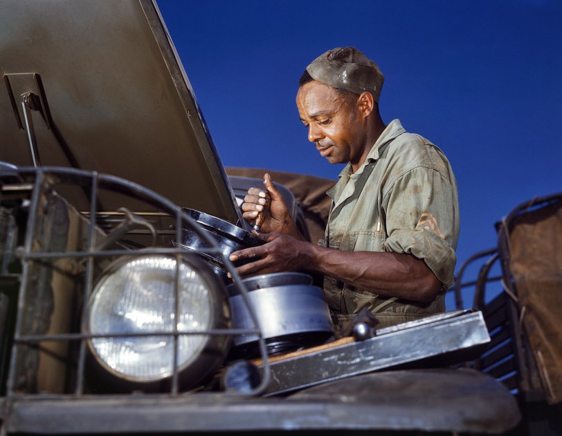 Army Mechanic: 1942 June 1942. Fort Knox, Kentucky. "A good job in the air cleaner of an Army truck. This Negro soldier, who serves as truck driver and mechanic, plays an important part in keeping Army transport fleets in operation." View full size. 4x5 Kodachrome transparency by Alfred Palmer for the Office of War Information.