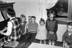 1961 (approx) Brownsburg, Indiana at our ancestral farm house. I'm the boy in the sweater. My sister is to my left and three of our cousins are pictured along with their mother playing the piano. I also see Grandma reflected in the window. My Dad was the photographer.

Singing carols at the farm house was a highlight of the holiday family gathering and welded for all time the emotions of Christmas to Christmas music for me.