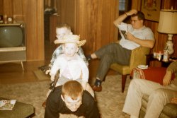 My brother (front) and I are "horseback riding" our father at Christmastime 1958, in Connecticut. We are armed with decidedly urban-looking weapons despite my brother's rustic cowboy hat. One of my uncles (seated) may have been consulting the TV Guide in the lower right corner, for the week of December 20-26, 1958, to decide what to watch on the gigantic--for its time--television set. 

Photograph by my grandfather, Edward Butler, whose work has previously been featured on Shorpy. Scanned February 2021 from a 35mm Kodachrome slide. 