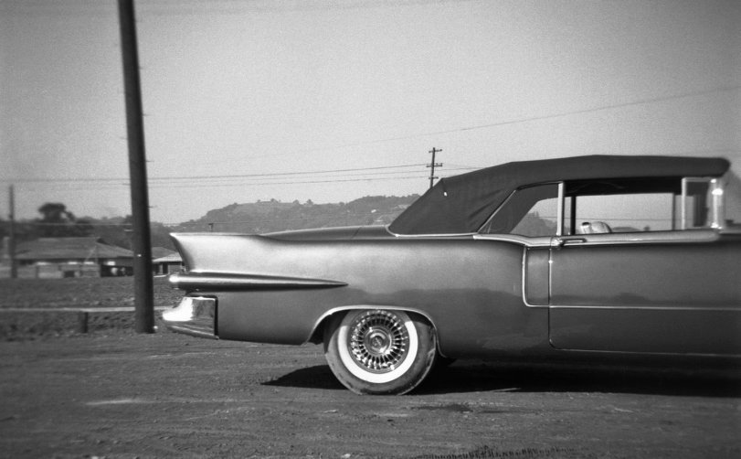 Larkspur Eldorado: 1955 1955 Cadillac Eldorado, photographed in the fall of that year by the nine-year-old me, then at the height of my kidhood car fascination. You can tell the part of the car that fascinated me most by how I aimed the camera. I also talked my brother into taking a Kodachrome slide of it. We were on one of the walks we were wont to take around our home town of Larkspur, California. This shot also captures, at the left, a significant moment in Larkspur history: the building of the first homes in the first major post-war housing development, Hillview Gardens. The houses sold in the low 20Ks. The following year the first kids from there started showing up in my classes at Larkspur-Corte Madera School. View full size.