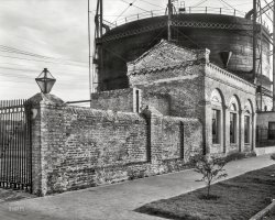 &nbsp; &nbsp; &nbsp; &nbsp; An old-school gasworks (back in the days before the widespread use of natural gas) where coal was heated to produce "city gas" or "illuminating gas," which was so poisonously toxic that people inhaled it to commit suicide ("taking the gas pipe"). The tank-like structure, called a gasometer or gas holder, telescoped up and down depending on how much gas was inside, its weight serving to pressurize the system and push gas through the lines.
1937. "Charlotte Street Gas Works, Charleston, South Carolina." 8x10 inch acetate negative by Frances Benjamin Johnston. View full size.