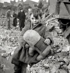 1940. "Abandoned boy holding a stuffed toy animal amid ruins following German aerial bombing of London." Photo by the versatile Toni Frissell. View full size.