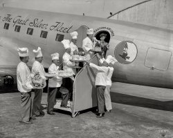October 4, 1938. "Cakes for sky riders. Air travelers leaving Washington Airport during National Air Travel Week, Oct. 2 through 9, are being given a special treat. Cakes baked from their favorite recipes are being put aboard each plane by chefs of the leading hotels in the Capital. Marjorie McKinnon, Eastern Airline hostess, is pictured receiving the delicacies from (left to right) Theophile Homberger, Hotel Hamilton; Eddie Weber, Shoreham Hotel; Joseph Cattaneo, Hotel Washington; Fritz Meissner, Hay-Adams; Abraham Grob, Wardman Park; Joseph Tucci, Raleigh; Jacques Haerringer, Shoreham; Otto Merz, Willard." View full size.