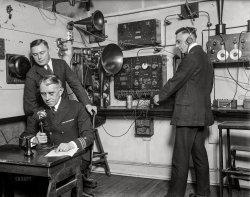 January/February 1923. "Headquarters of the U.S. Coast Guard are using a unique method for distributing news of their service by means of radio. Capt. F.C. Billard, aide to the commandant, is shown broadcasting. Lt. F.A Zensler is coaching him from the receiving set, which is being used by Lt. E.M. Webster (with earpieces)." Harris & Ewing glass negative. View full size.