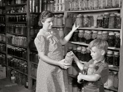 September 1941. "Mrs. Harvey Renninger and son in her home with canned goods. Two River Non-Stock Cooperative, FSA co-op. Waterloo, Nebraska." Medium format acetate negative by Marion Post Wolcott for the Farm Security Administration. View full size.
