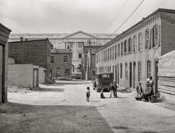 &nbsp; &nbsp; &nbsp; &nbsp; A scene last glimpsed here, but without the trolley.
September 1941. Washington, D.C. "Schoots Court [i.e., Schott's Alley] with Senate Office Building in background. Four very small dark rooms rent for fifteen and eighteen dollars per month with water and privy in yard. It used to rent for six and eight dollars. Frank Coles and his friend are sitting on the bench. He was a cement plasterer but has been on relief during the past year. He has frequent heart attacks and his feet and ankles are all swollen. Doctor advises a chicken and lamb diet, no pork or beef, but he doesn't even have money to buy fuel. He can't get waited on in a clinic or get to one. He waited from before 11 until 4 p.m. but still could not see a doctor. He has been in Washington since 1906." Medium format acetate negative by Marion Post Wolcott for the Farm Security Administration. View full size.