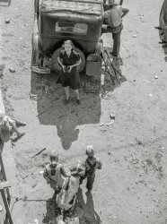 July 1940. Berrien County, Michigan. "Migrant agricultural workers -- 'fruit tramps' harvesting cherries and strawberries. Miserable housing in company shacks, cabins, tents, trucks, abandoned farm buildings, small children in fields with parents. Migrant mother from Arkansas taking a picture of the family before moving on to new work location." Photo by John Vachon for the Farm Security Administration. View full size.