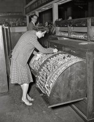 November 1942. "Washington, D.C. Clerk and ticket seller searching for reservations at the Union Station." Acetate negative by Gordon Parks, Office of War Information. View full size.