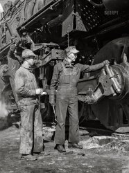 March 1943. "Clovis, New Mexico. Private Clarence Stephens of Streator, Illinois, a member of the U.S. Army Railroad Battalion stationed at Clovis, with Sidney Mack, engine inspector at the Atchison, Topeka and Santa Fe Railroad shops. They are inspecting one of the 5000 Class freight engines." Acetate negative by Jack Delano,  Office of War Information. View full size.