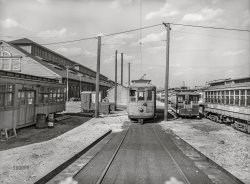April 1943. Baltimore, Maryland. "Transportation for war-swollen population. The yard of Washington Terminal, maintenance plant of the Baltimore Transit Co. From left to right: old trolley made into a smoker for employees; a work car; and an old horse car. Baltimore Trust building on the horizon." Photo by Marjory Collins, Office of War Information. View full size.