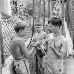 July 1943. "Glen Echo, Maryland. An attendant washing the sand from people who are going to the swimming pool from the beach at Glen Echo amusement park." Photo by Esther Bubley for the Office of War Information. View full size.