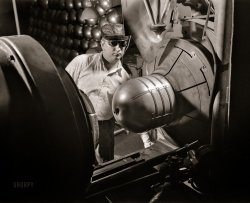 February 1942. Firestone Rubber plant in Akron, Ohio. "Conversion. Beverage containers to aviation oxygen cylinders. Before completion of the fourth and final welding operation in the manufacture of shatterproof oxygen cylinders for high altitude flying, all straps are subjected to physical tests to determine the strength of the weld. Occasional radiographic inspections are made to insure the quality of workmanship after the two halves of the cylinder are brought together in this atomic welding machine and made one unit. Here, the operator has just completed the union and is about to remove the whole cylinder." 4x5 nitrate negative by Alfred Palmer for the Office of War Information. View full size.