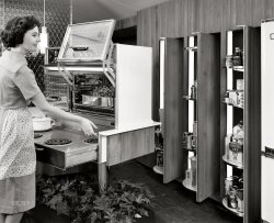 November 1960. New York. "General Motors Motorama '61 at the Waldorf-Astoria. 'Ideas for Living' exhibit features model kitchen with two-oven Frigidaire Flair range with pull-out burners, mounted on a slim pedestal rising from a bed of growing plants. 'About-Face' pantry has hidden shelves that pivot out from storage wall at the touch of a button." View full size.